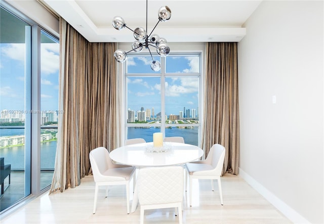 dining area featuring an inviting chandelier, a water view, and light hardwood / wood-style floors