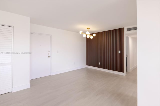 spare room with light hardwood / wood-style floors and a notable chandelier