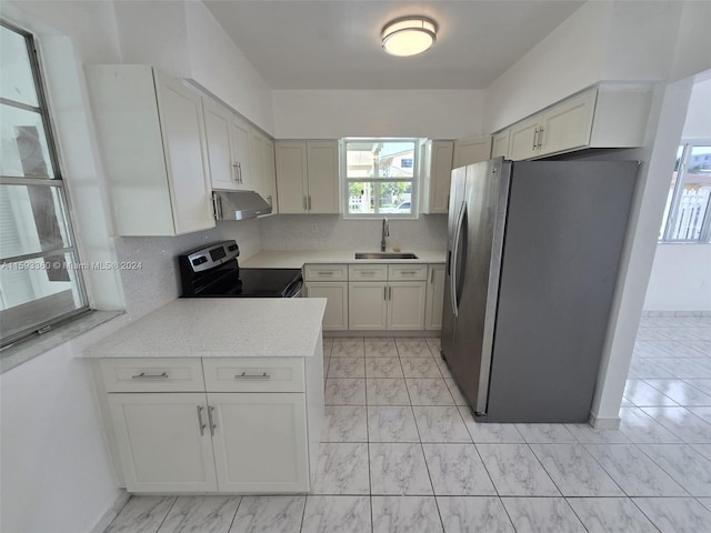 kitchen featuring sink, tasteful backsplash, stainless steel fridge, black electric range oven, and exhaust hood