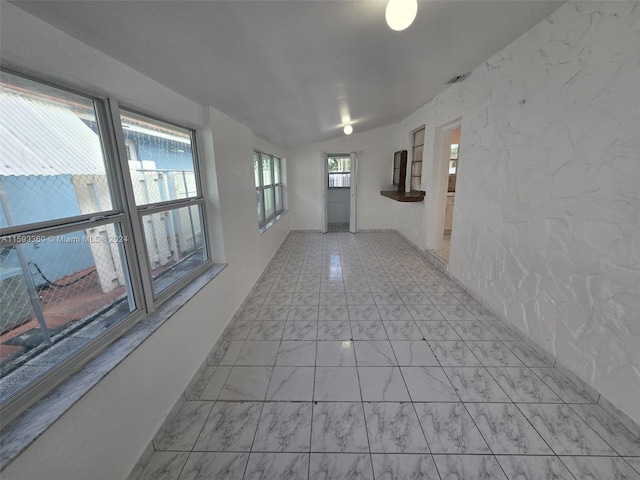 corridor with plenty of natural light and lofted ceiling