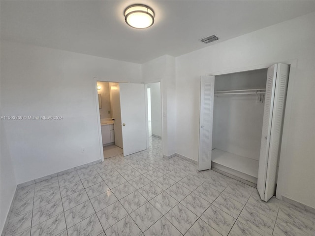 unfurnished bedroom featuring ensuite bath and a closet