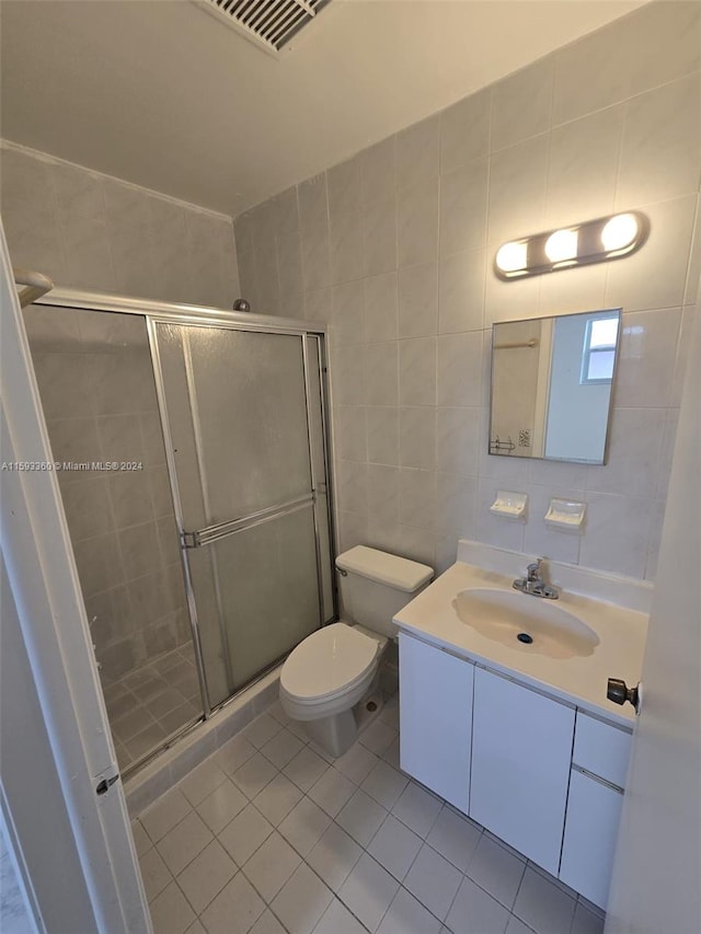 bathroom featuring walk in shower, tile patterned flooring, vanity, toilet, and tile walls