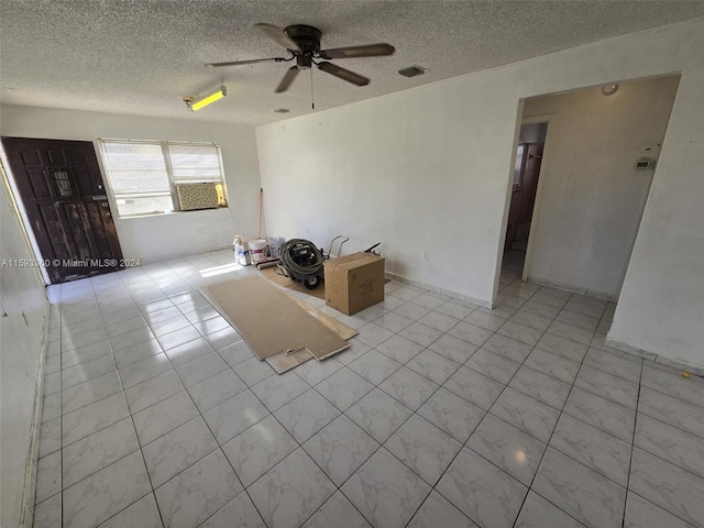 interior space with a textured ceiling, ceiling fan, and light tile patterned floors