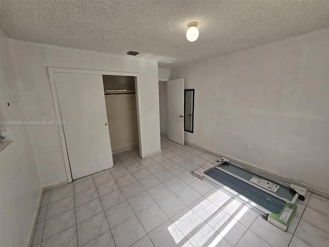 unfurnished bedroom with light tile patterned flooring, a textured ceiling, and a closet