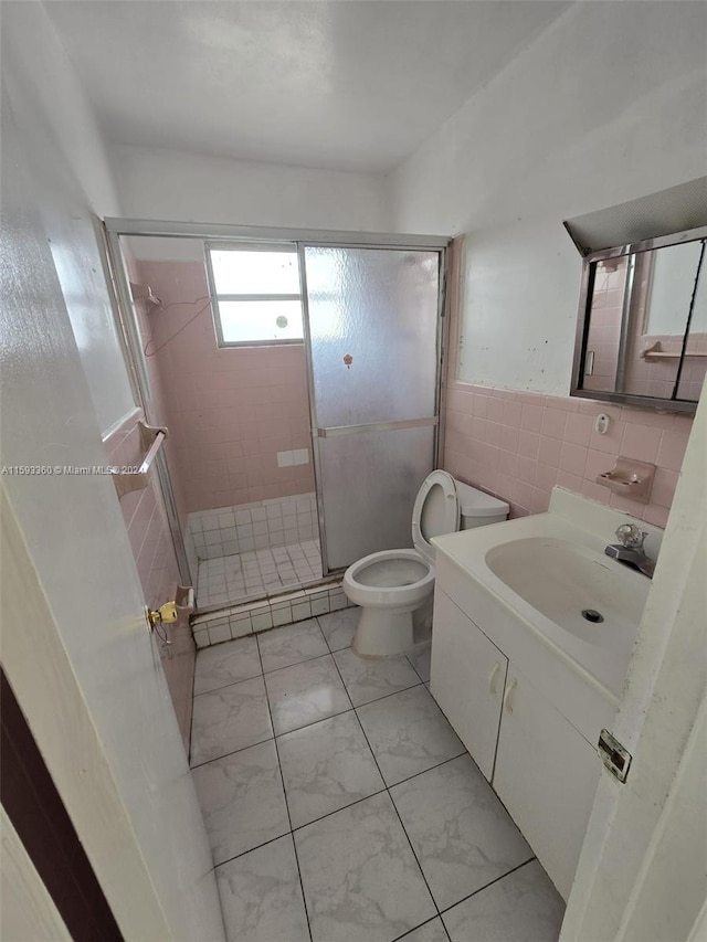 bathroom with walk in shower, tile walls, vanity, and toilet