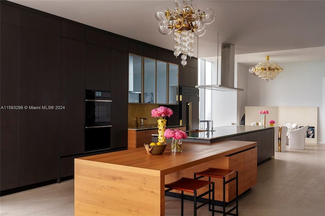 kitchen with wall chimney exhaust hood, an inviting chandelier, double wall oven, and stainless steel built in refrigerator