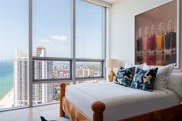 bedroom featuring a water view, expansive windows, and hardwood / wood-style flooring