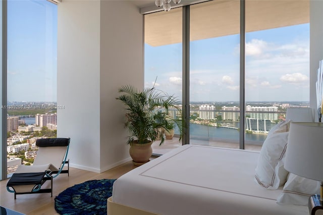 bedroom with hardwood / wood-style floors and a water view