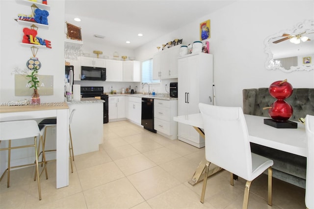 kitchen with light tile patterned flooring, white cabinets, a kitchen breakfast bar, and black appliances