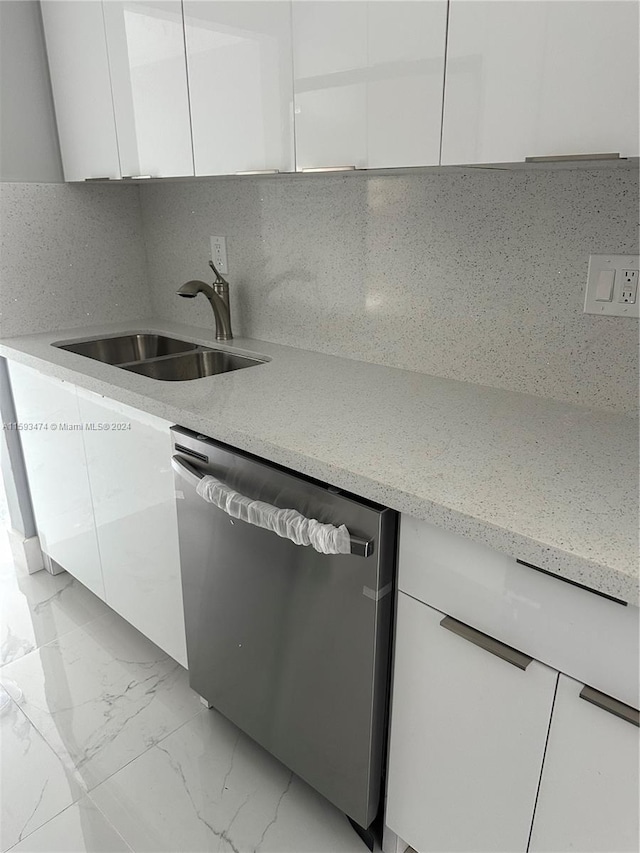 kitchen featuring sink, backsplash, stainless steel dishwasher, light stone countertops, and white cabinetry