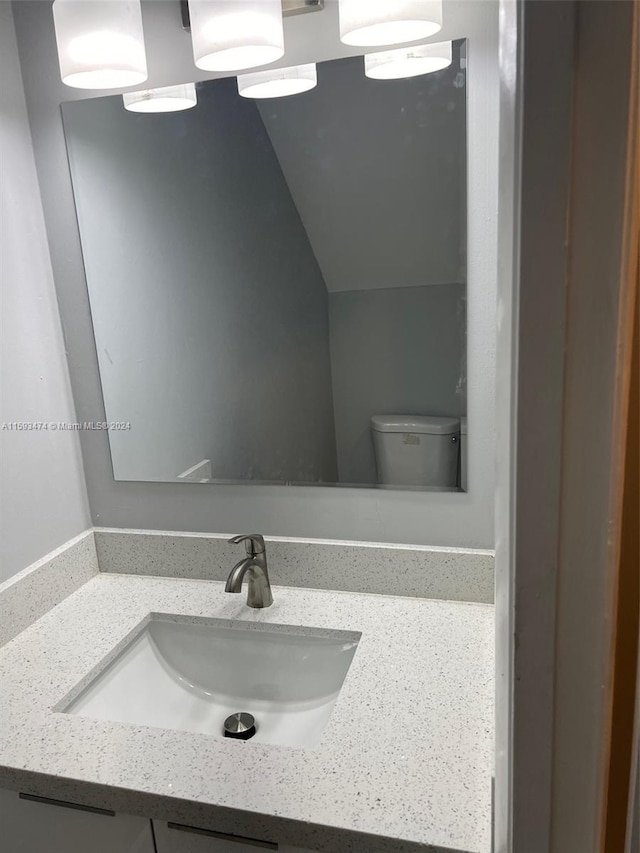 bathroom with lofted ceiling, toilet, and vanity