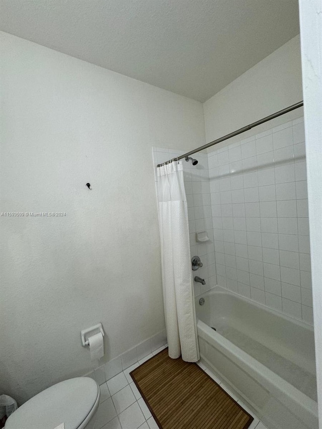 bathroom featuring tile flooring, shower / tub combo with curtain, and toilet