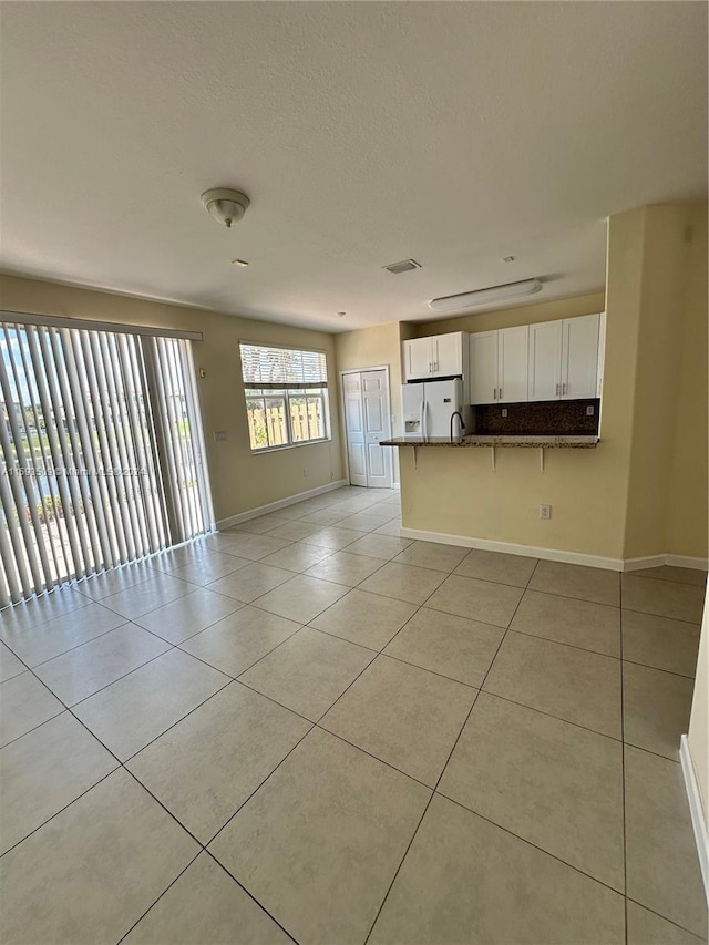 unfurnished living room featuring sink and light tile floors