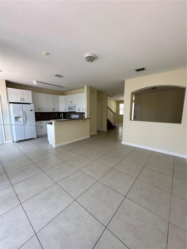 unfurnished living room featuring sink and light tile floors