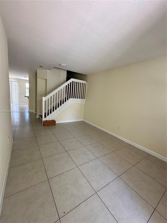 tiled empty room with a textured ceiling