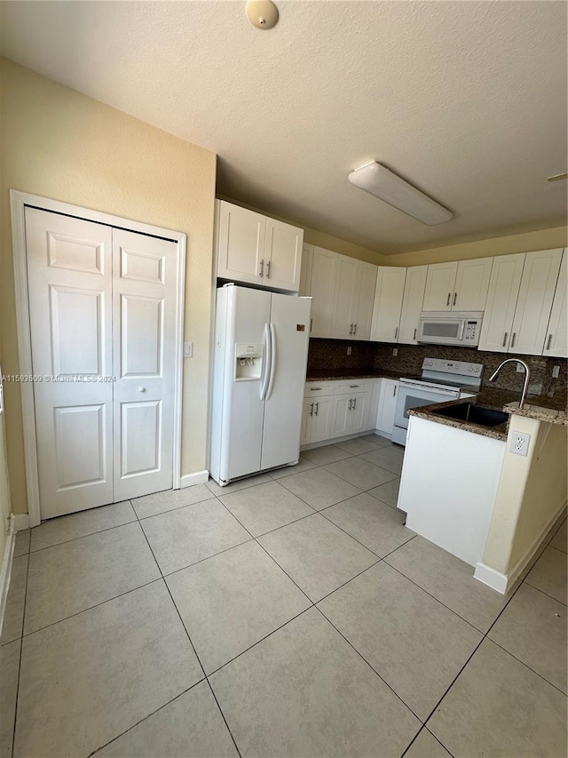 kitchen featuring white cabinetry, a textured ceiling, white appliances, sink, and light tile floors