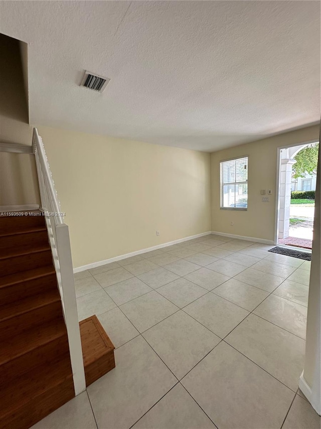 unfurnished room with a textured ceiling and light tile flooring