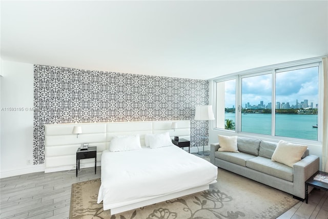 bedroom with a water view and light hardwood / wood-style floors