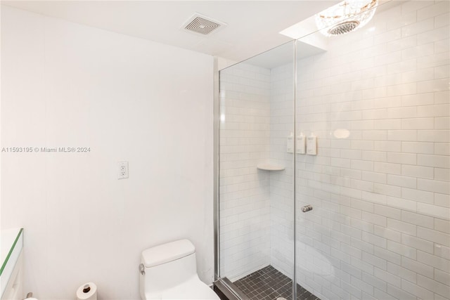 bathroom with a shower with shower door and toilet