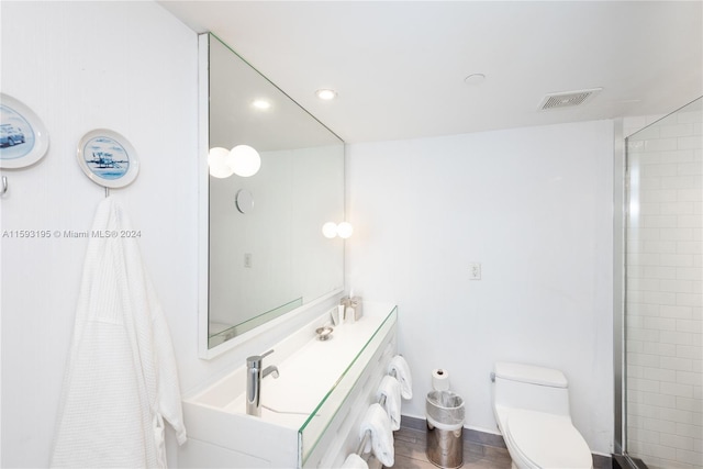 bathroom featuring toilet, a tile shower, and vanity