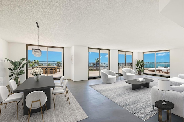 living room featuring a textured ceiling, a wall of windows, and a notable chandelier