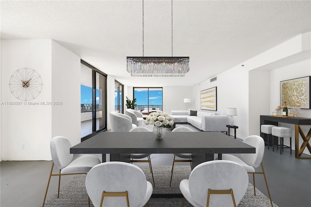 dining room featuring a wall of windows, a notable chandelier, concrete floors, and a textured ceiling