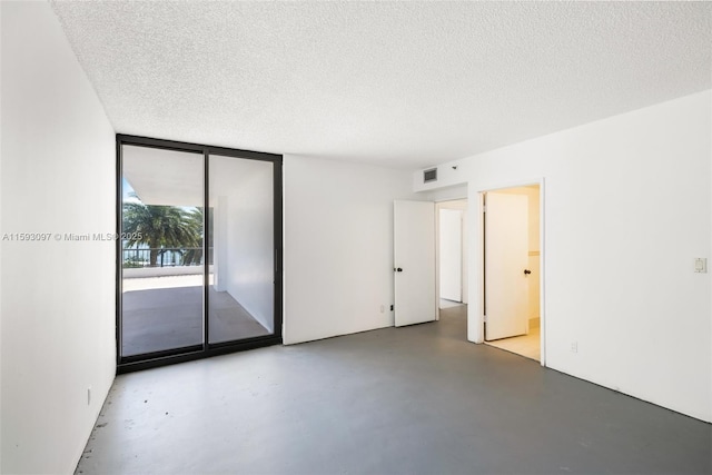 spare room with a textured ceiling and floor to ceiling windows