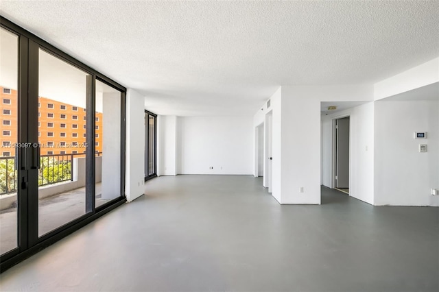 empty room with a textured ceiling and a wall of windows