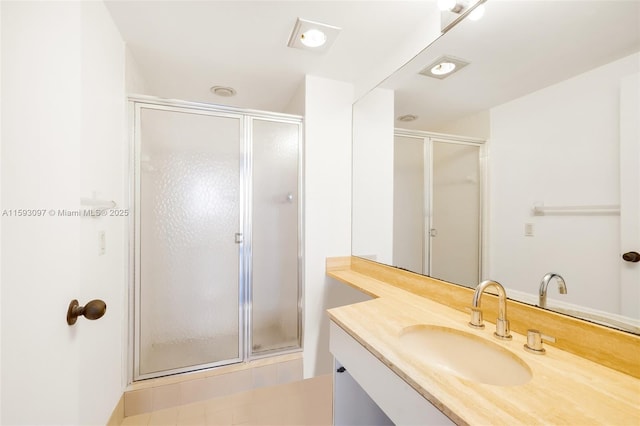 bathroom featuring a shower with door and vanity