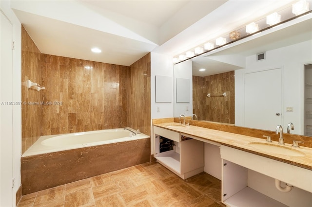 bathroom featuring tiled bath and vanity