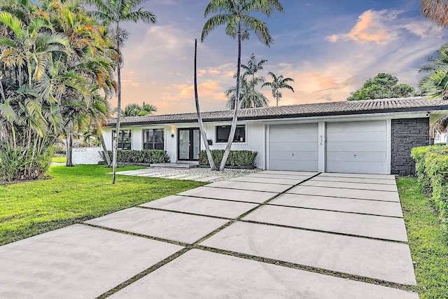 single story home with a garage and a lawn