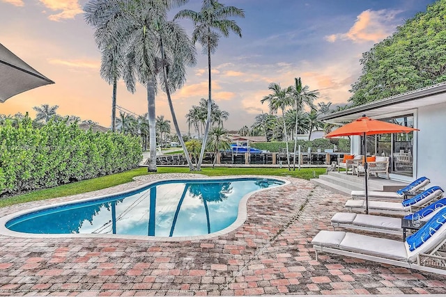 pool at dusk featuring a patio