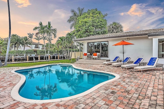 pool at dusk featuring a patio