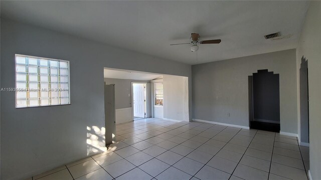 tiled empty room featuring a wealth of natural light and ceiling fan