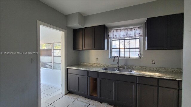 kitchen featuring a healthy amount of sunlight, dark brown cabinetry, light tile patterned floors, and sink