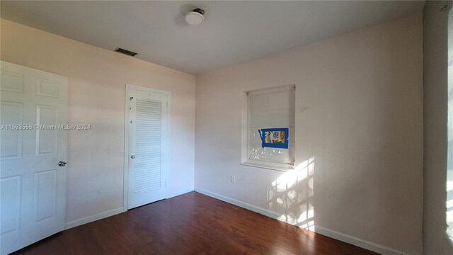 unfurnished bedroom featuring a closet and dark hardwood / wood-style floors