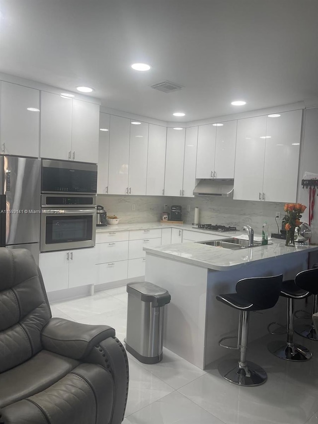 kitchen with white cabinets, appliances with stainless steel finishes, and a breakfast bar