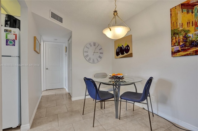 tiled dining area with a textured ceiling