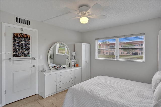 bedroom with a textured ceiling, ceiling fan, light tile floors, and multiple windows