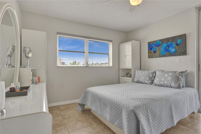 tiled bedroom with ceiling fan and a textured ceiling