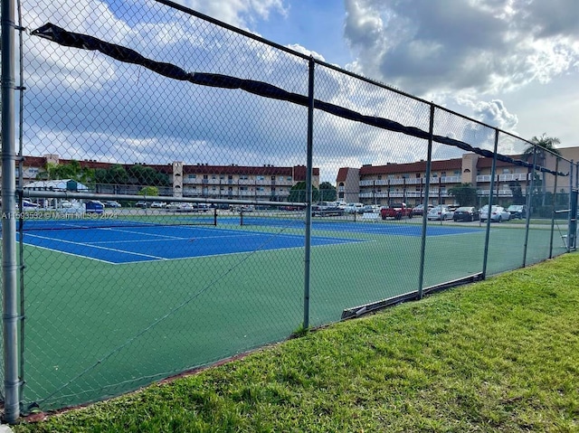 view of tennis court featuring a lawn