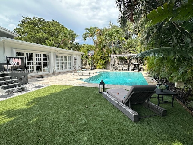 view of swimming pool with french doors, a patio, and a lawn