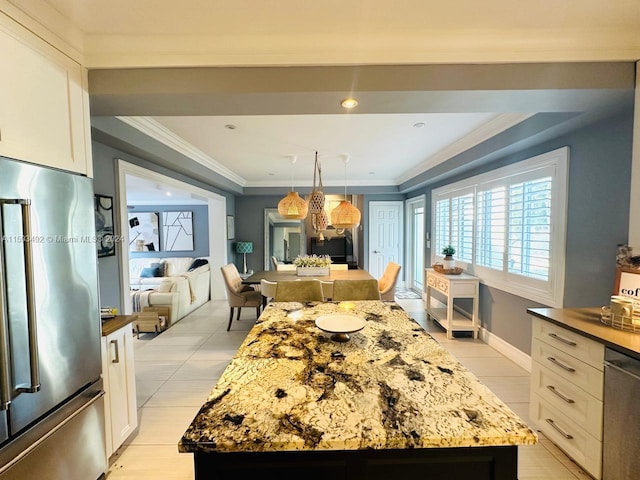 kitchen featuring dark stone counters, ornamental molding, a center island, white cabinets, and appliances with stainless steel finishes