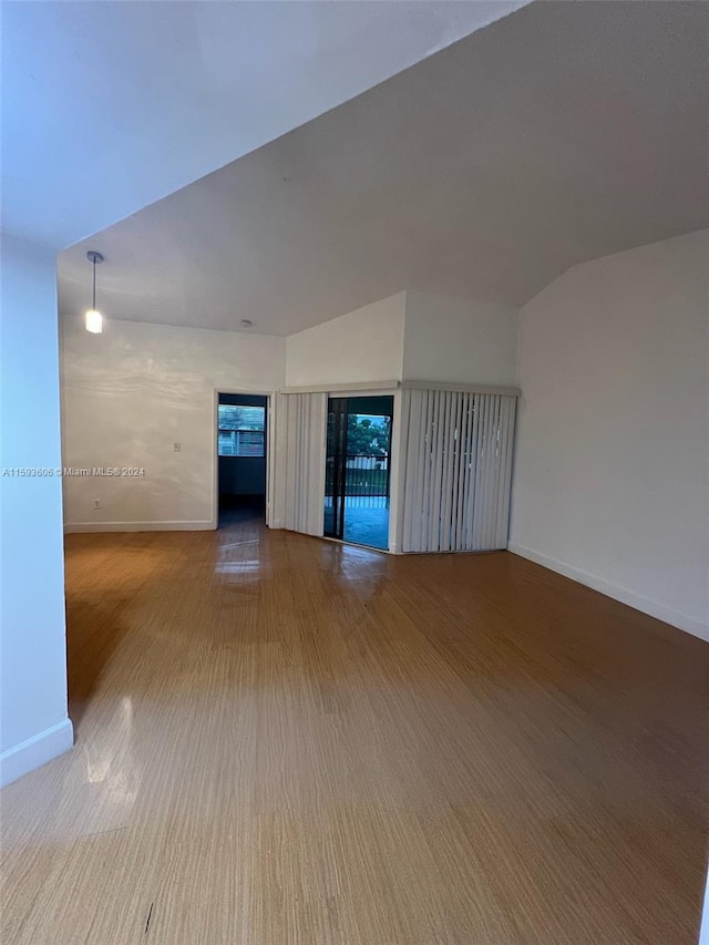 empty room with hardwood / wood-style flooring and vaulted ceiling