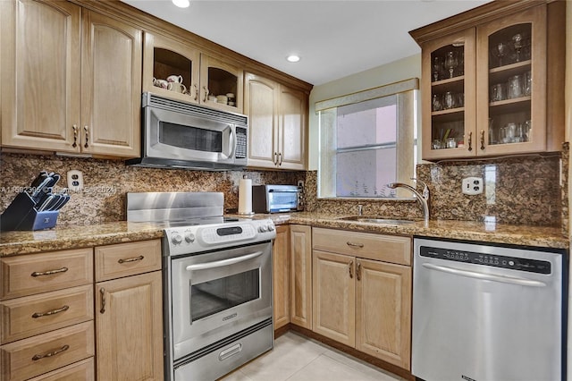 kitchen with backsplash, appliances with stainless steel finishes, light tile flooring, and stone countertops