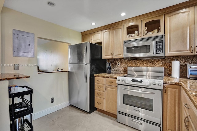 kitchen with stainless steel appliances, light brown cabinetry, light stone counters, backsplash, and light tile floors