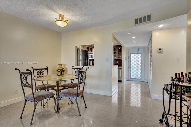 dining room with a textured ceiling and light tile floors