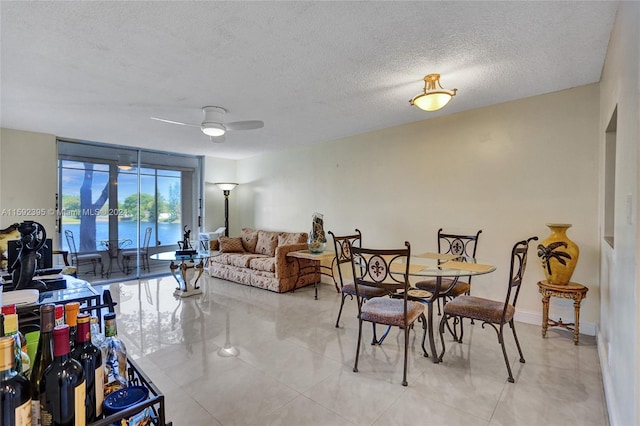 tiled dining room featuring a water view, ceiling fan, and a textured ceiling