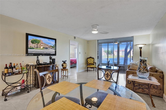 dining area with a water view, light tile flooring, ceiling fan, and a textured ceiling