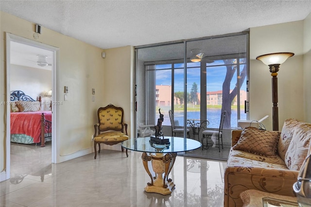 living room featuring a healthy amount of sunlight, a water view, and light tile floors